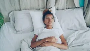 person laying in bed with hands crossed